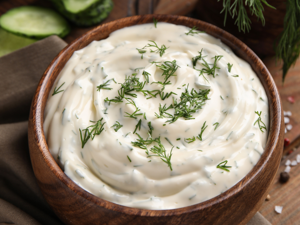 A bowl of thick and creamy yogurt dill sauce with fresh herbs and spices, perfect for dipping or as a condiment.
