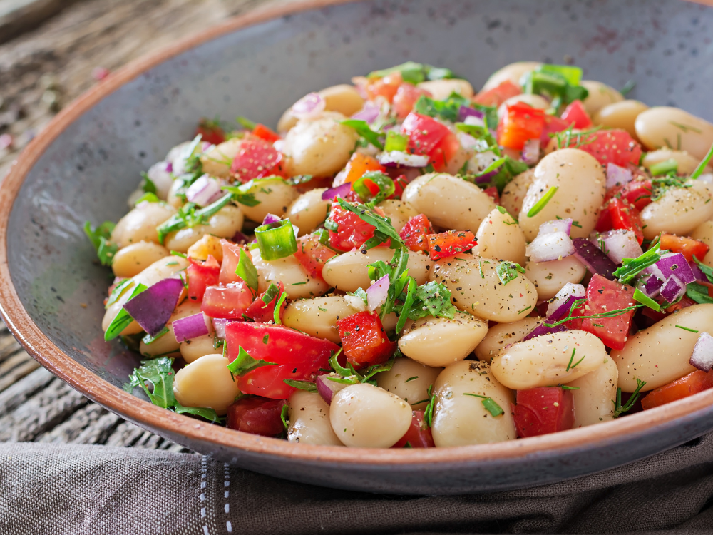 White bean salad with cherry tomatoes and red onions, drizzled with a zesty dressing.