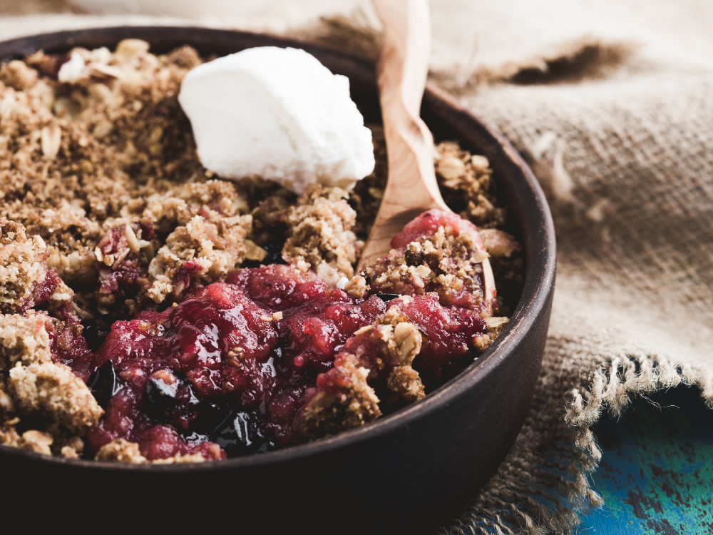 A delicious and rustic dessert consisting of baked fruit, topped with a crumbly mixture of oats and cinnamon. The dish is served in a large baking dish and garnished with a scoop of vanilla ice cream.