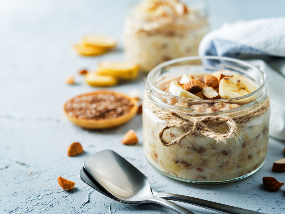 A bowl of cooked oats topped with sliced bananas, almond slices, and a drizzle of honey.