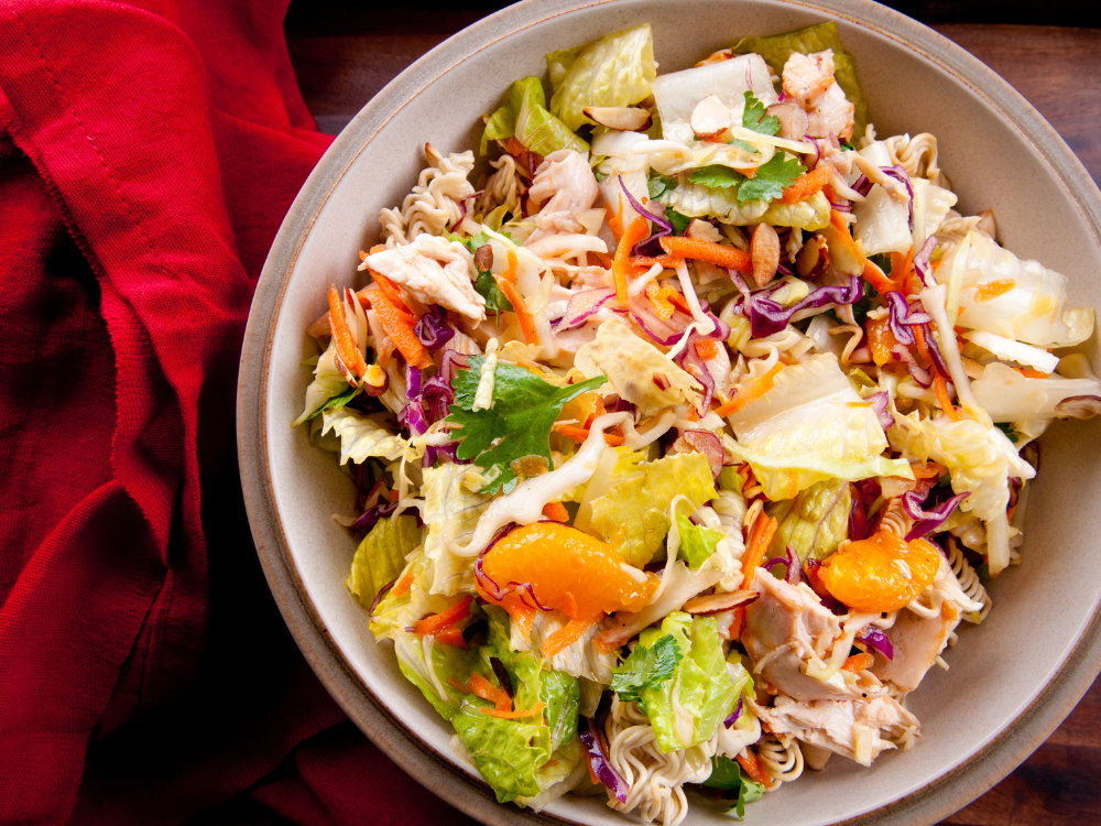 A bowl of Mandarin Chicken Salad featuring fresh greens, slices of grilled chicken, and mandarin oranges
